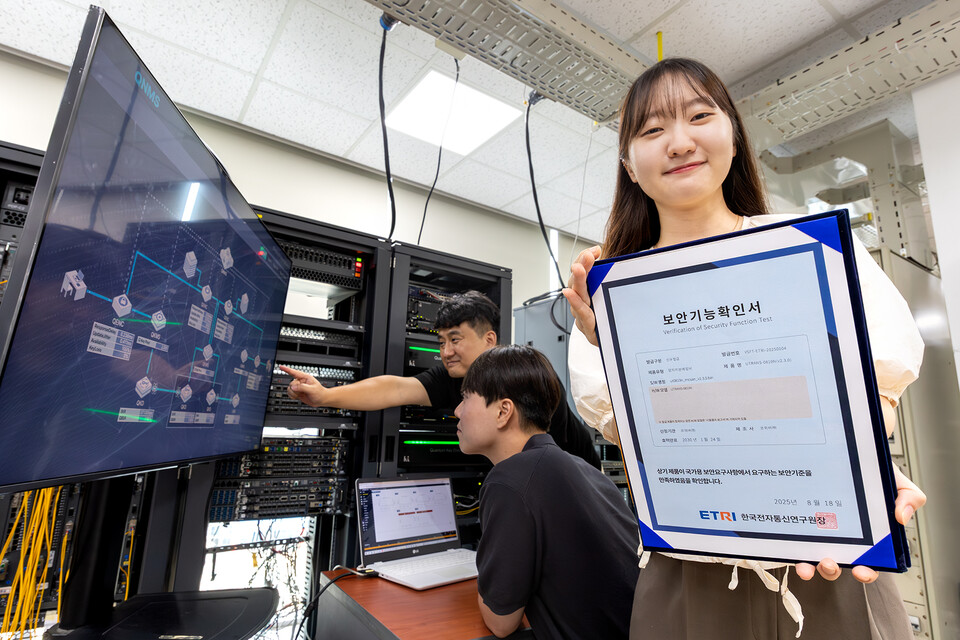 KT와 코위버 직원이 양자키분배 기술 적용 장비를 점검하며 보안 인증서를 소개하는 모습. (사진=KT)